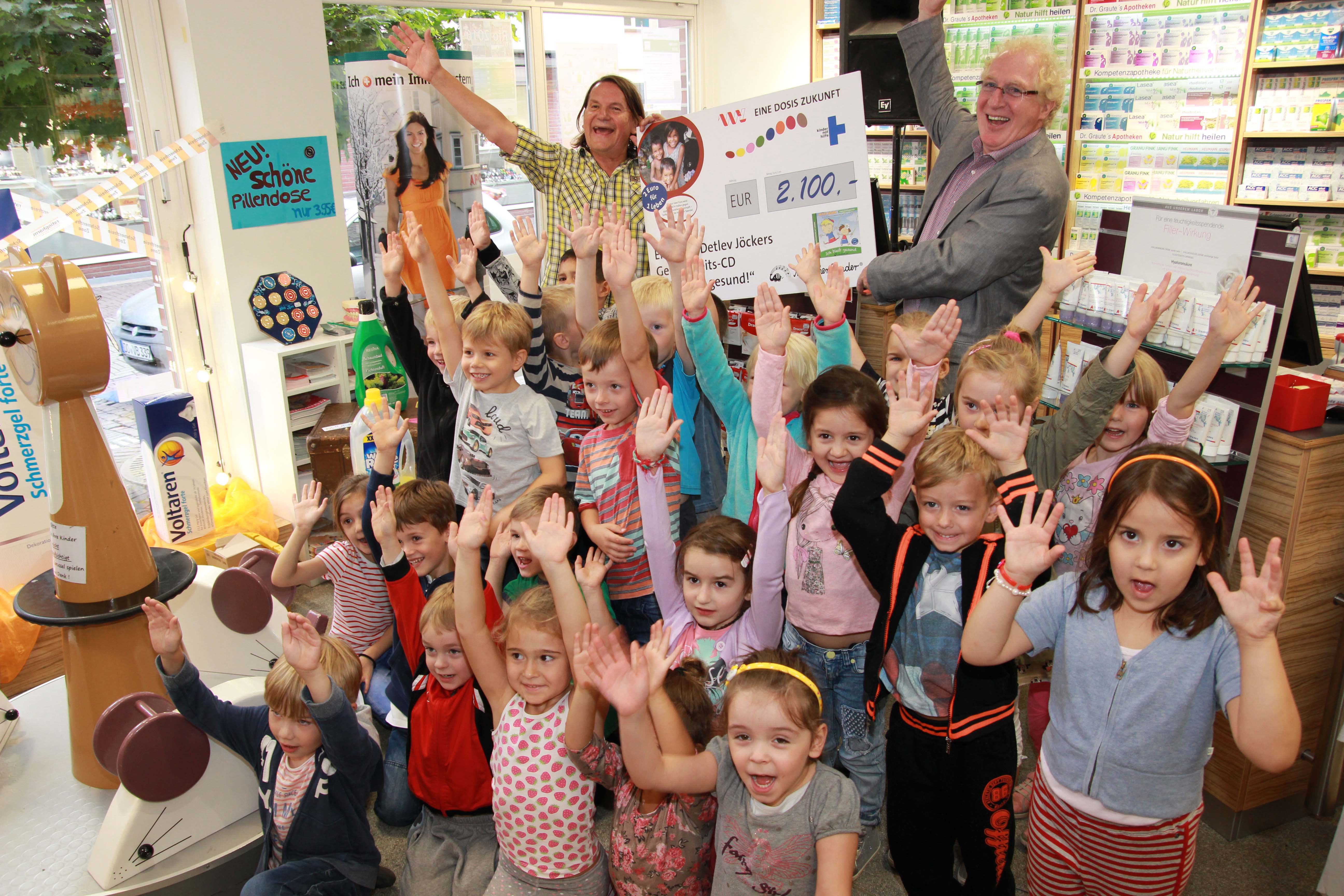 Detlev Jöcker (links) überreichte einen Spendenscheck an Dr. Wolfgang Graute, Vorstandsmitglied der Apothekerkammer Westfalen-Lippe - umringt von den Kids des Overberg-Kindergartens.